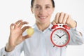 Woman is holding golden bitcoin and alarm clock