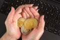 Woman holding golden coloured cryptocurrency coins in her hands over black laptop keyboard Royalty Free Stock Photo