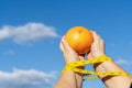 woman holding a grapefruit in her hands with a tape measure ,concept of a diet slave