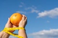 woman holding a grapefruit in her hands with a tape measure ,concept of a diet slave