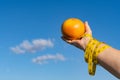 woman holding a grapefruit in her hands with a tape measure ,concept of a diet slave