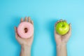 Woman holding green apple and pink donut, female choose between fruit is Healthy food and sweet is unhealthy junk foods. Dieting, Royalty Free Stock Photo