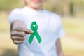 Woman holding green Ribbon for supporting people living and illness. Liver, Gallbladders bile duct, kidney Cancer and Lymphoma