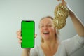 Woman holding green screen phone New Year Joy of waiting there is a place for text holds Christmas tree toys in one hand Royalty Free Stock Photo