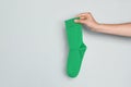 Woman holding green sock against grey background, closeup