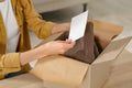 Woman holding greeting card near parcel with Christmas gift indoors, closeup Royalty Free Stock Photo