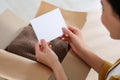 Woman holding greeting card near parcel with Christmas gift indoors, closeup Royalty Free Stock Photo