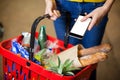 Woman holding groceries and mobile phone in supermarket Royalty Free Stock Photo