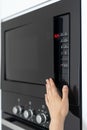 Woman holding hand on black microwave door Royalty Free Stock Photo