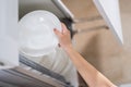 Woman holding in hand plate and getting out or putting in it in kithen or dishwasher shelf.