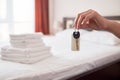 Woman holding in hand room key with blank label at hotel suite, copy space. Bedroom interior in blur Royalty Free Stock Photo