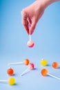 Woman holding in hand upside down lollipop candy on blue background