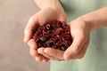 Woman holding handful of tasty cranberries on color background, closeup.