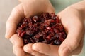 Woman holding handful of tasty cranberries on color background, closeup