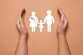 Woman holding hands around paper silhouette of family on coral background, top view. Insurance concept Royalty Free Stock Photo