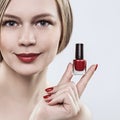 Woman holding hands with a bottle of red nail polish, red lipstick on her lips and red nails. Royalty Free Stock Photo