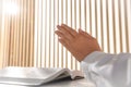 Woman holding hands clasped while praying over Bible at white table indoors, closeup Royalty Free Stock Photo