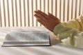 Woman holding hands clasped while praying over Bible at white table indoors, closeup Royalty Free Stock Photo