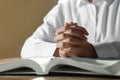 Woman holding hands clasped while praying over Bible at wooden table, closeup Royalty Free Stock Photo