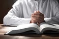 Woman holding hands clasped while praying over Bible at wooden table, closeup Royalty Free Stock Photo