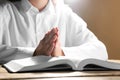 Woman holding hands clasped while praying over Bible at wooden table, closeup Royalty Free Stock Photo