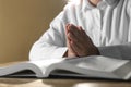 Woman holding hands clasped while praying over Bible at wooden table, closeup Royalty Free Stock Photo