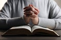 Woman holding hands clasped while praying over Bible at wooden table, closeup Royalty Free Stock Photo