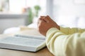 Woman holding hands clasped while praying at wooden table with Bible indoors, closeup. Space for text Royalty Free Stock Photo