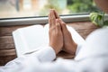 Woman holding hands clasped while praying at wooden table with Bible, closeup Royalty Free Stock Photo