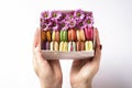 Woman holding in hands gift box with colorful french macaroons with flowers on white background Royalty Free Stock Photo