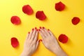 Woman holding hands near rose petals on color background. Beautiful nail polish Royalty Free Stock Photo