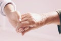 Woman holding hands with senior lady on light background, closeup. Royalty Free Stock Photo