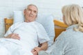 Woman holding hands with sick husband lying on bed in clinic Royalty Free Stock Photo