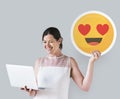 Woman holding a heart eyes emoticon and a laptop Royalty Free Stock Photo