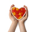 Woman holding heart shaped bowl with delicious gummy raspberry candies on white background, top view Royalty Free Stock Photo