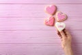 Woman holding heart shaped cookie with word Love on wooden background, top view. Royalty Free Stock Photo