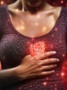 Woman is holding her chest with both hands. She appears to be in pain or distress as she clutches her heart area tightly