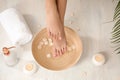 Woman holding her feet over bowl with water and rose petals on floor, closeup. Royalty Free Stock Photo