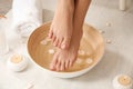 Woman holding her feet over bowl with water and rose petals on floor, closeup. Royalty Free Stock Photo