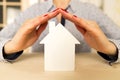 Woman holding her hands above white small model house as a sign Royalty Free Stock Photo