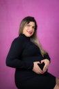 Woman holding her hands in a heart shape on her pregnant belly Royalty Free Stock Photo