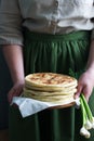 Woman holding in her hands traditional in different countries pies stuffed with cheese and herbs and fresh garlic.