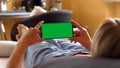 Woman Holding a Horizontal Green Screen Smartphone, Lying on the Bed