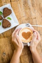 Woman holding hot cup of coffee, with heart shape and chocolate Royalty Free Stock Photo