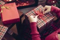 Woman holding huge gift box sitting near christmas tree and fireplace. Packing handmade christmas gifts.