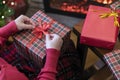 Woman holding huge gift box sitting near christmas tree and fireplace. Packing handmade christmas gifts.