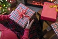 Woman holding huge gift box sitting near christmas tree and fireplace. Packing handmade christmas gifts.