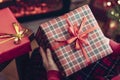 Woman holding huge gift box sitting near christmas tree and fireplace. Packing handmade christmas gifts.