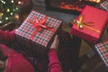 Woman holding huge gift box sitting near christmas tree and fireplace. Packing handmade christmas gifts.