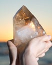 Woman holding huge natural Citrine Cathedral Quartz from Brazil in her hand at sunrise